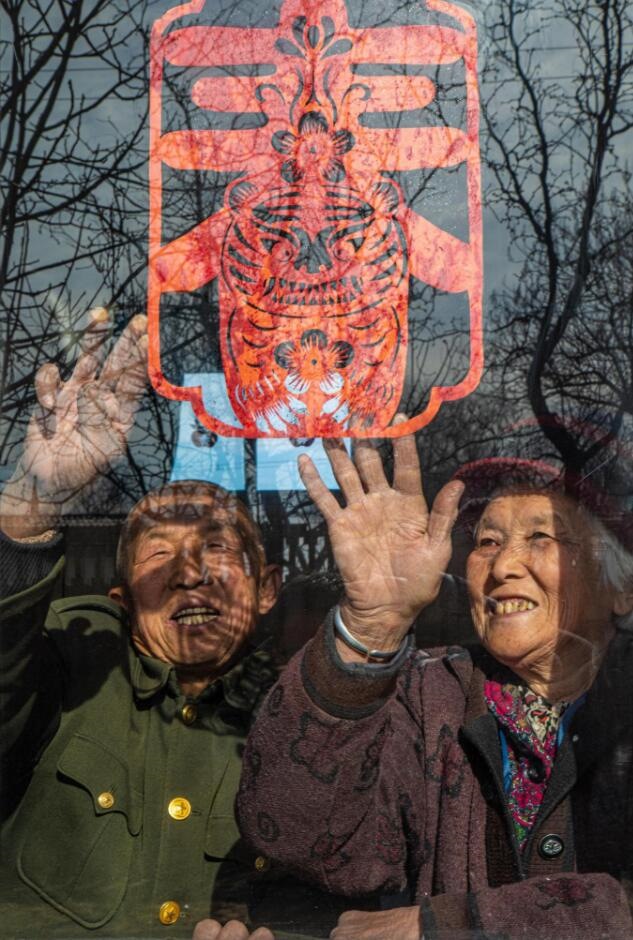 臘月里，霍州市師莊鄉(xiāng)馮南垣村村民師榮光(左)在災后重建的新家里貼窗花。(霍州市委宣傳部供圖)