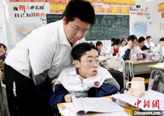 朱金祥(左)把鐘華強放到課堂座位上后，都要把他擺正好，確認安全后才回到自己的座位上。 卓忠偉 攝