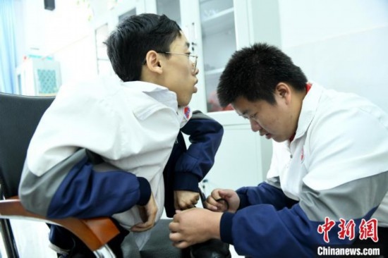 江西省南康中學北校區(qū)的高三學生朱金祥(右)正在給鐘華強(左)系好鞋帶。 卓忠偉 攝