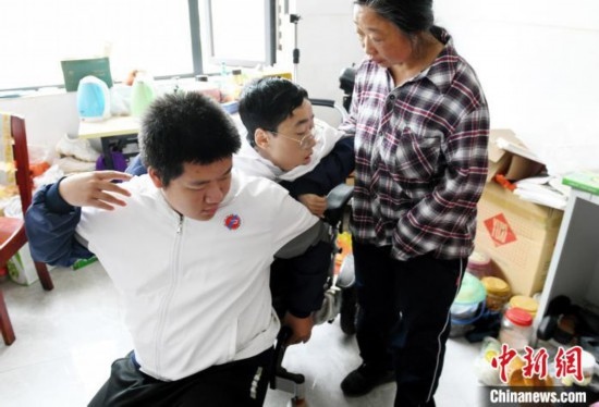 江西省南康中學北校區(qū)的高三學生朱金祥(左)來到學校給鐘華強母子安排的公寓，準備背他去課堂上課。 卓忠偉 攝