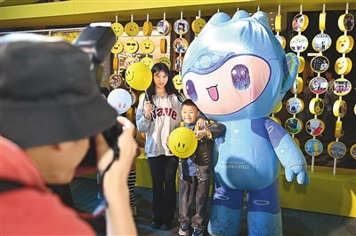 5月7日，在浙江省杭州市湖濱步行街“3D笑臉墻”前，攝影師為游客與杭州亞運(yùn)會(huì)吉祥物之一“宸宸”拍攝合影。
