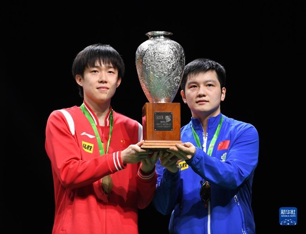 5月27日，樊振東（右）/王楚欽在頒獎儀式上高舉獎杯慶祝。當日，在南非德班進行的2023年世界乒乓球錦標賽男雙決賽中，中國組合樊振東/王楚欽以3比0戰(zhàn)勝韓國組合張禹珍/林鐘勛，奪得冠軍。新華社記者 李亞輝攝