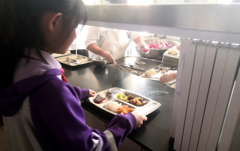 伊金霍洛旗第一小學(xué)學(xué)生正在打飯，今天的飯菜是三菜一湯外加水果，學(xué)生可以多次盛取，吃飽為止。人民網(wǎng)記者 孫博洋攝