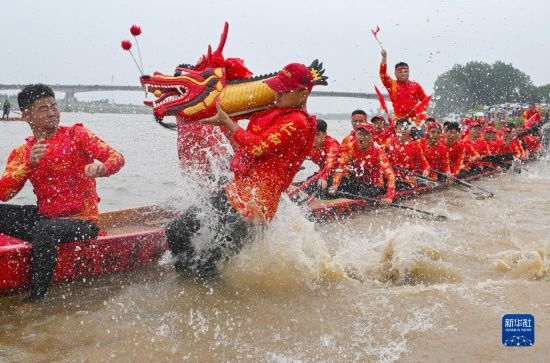 6月22日，在湖南省岳陽市湘陰縣湘江臨資口水域，參加龍舟賽的隊(duì)員接“龍頭”下水。