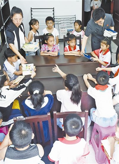  圖④：法院干警為留守兒童發(fā)放暑假讀物。