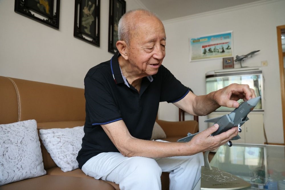 ↑2023年7月24日，新中國(guó)第一代飛行員陶偉在家中擦拭殲-20飛機(jī)模型。新華社發(fā)（張瑞 攝）