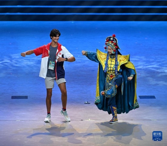 7月29日，美國運動員杜恩（左）在聯(lián)歡會現(xiàn)場與川劇演員互動。新華社記者 蔡湘鑫 攝