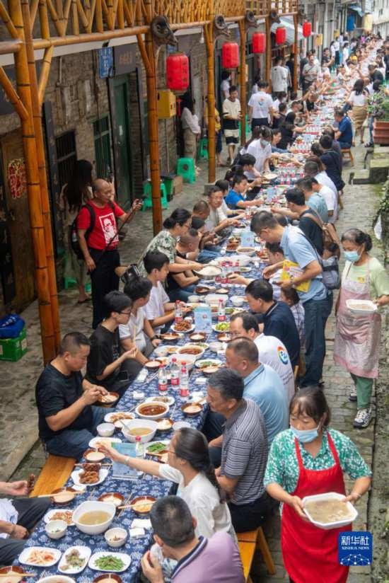 7月29日，在重慶市綦江區(qū)安穩(wěn)鎮(zhèn)，人們?cè)凇懊缂曳蚬?jié)”上吃長(zhǎng)桌宴。新華社記者 唐奕 攝
