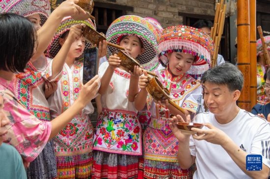 7月29日，在重慶市綦江區(qū)安穩(wěn)鎮(zhèn)，當(dāng)?shù)鼐用裨凇懊缂曳蚬?jié)”上用傳統(tǒng)習(xí)俗向游客表達(dá)祝福。新華社記者 唐奕 攝