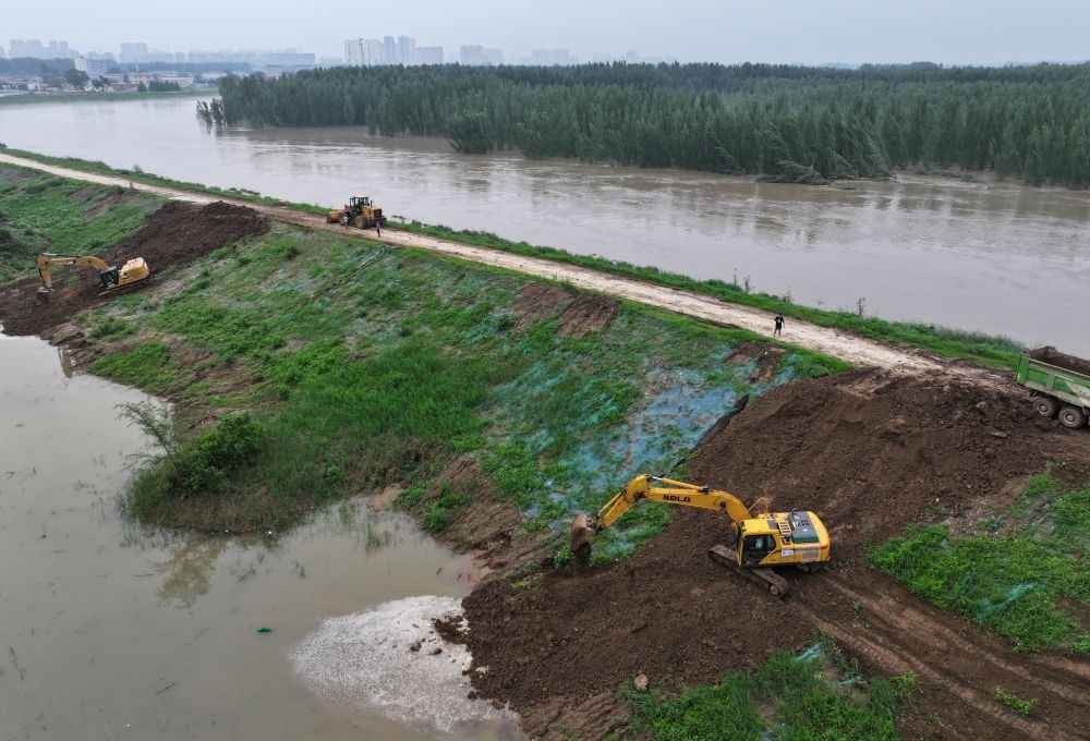 工人操作機(jī)械在白溝河左堤白溝新城高橋村段進(jìn)行除險(xiǎn)加固作業(yè)（8月4日攝，無(wú)人機(jī)照片）。新華社記者 朱旭東 攝