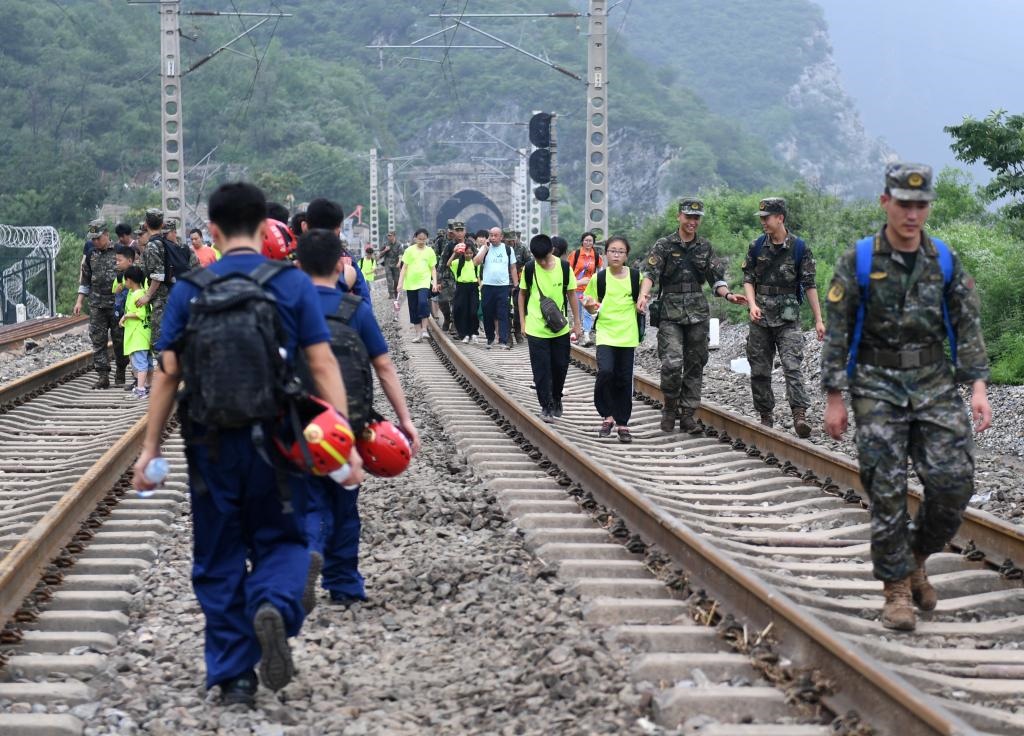 8月2日，部分滯留在北京市門(mén)頭溝山區(qū)受困列車(chē)的旅客，在救援人員幫助下前往轉(zhuǎn)運(yùn)客車(chē)。新華社記者張晨霖 攝