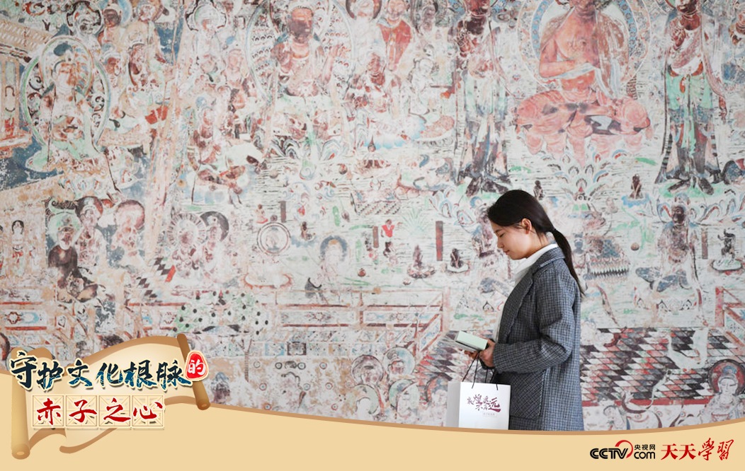 2023年4月25日，敦煌研究院文物數(shù)字化保護團隊創(chuàng)意營銷人員廖雪婷從一幅高保真復制壁畫前走過。