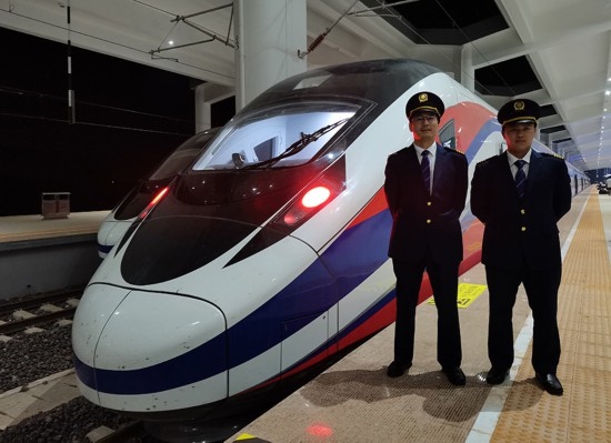 劉銀能（右一）與中國(guó)師父鄔俊鴻在動(dòng)車組前合影。受訪者供圖