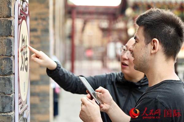 選手安德烈（俄羅斯）在老師指導(dǎo)下學(xué)習(xí)墻壁上張貼的生僻字。人民網(wǎng) 盧鵬宇攝