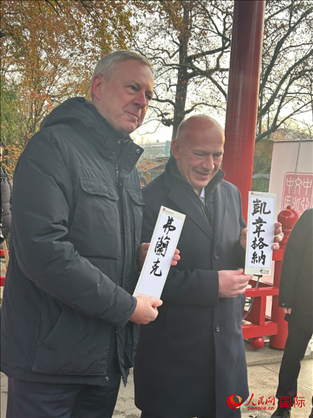 柏林市長韋格納（右）、動物園監(jiān)事會主席布魯克曼（左）手持中國文化中心工作人員現(xiàn)場手書的中文名字。人民網(wǎng)記者 徐馨攝