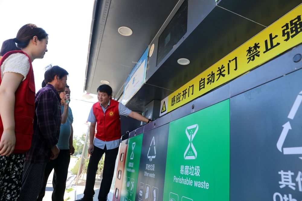 在安徽省合肥市長豐縣莊墓鎮(zhèn)棗林社區(qū)，志愿者指導居民使用智能垃圾分類回收設備（2023年9月1日攝）。新華社記者 曹力 攝