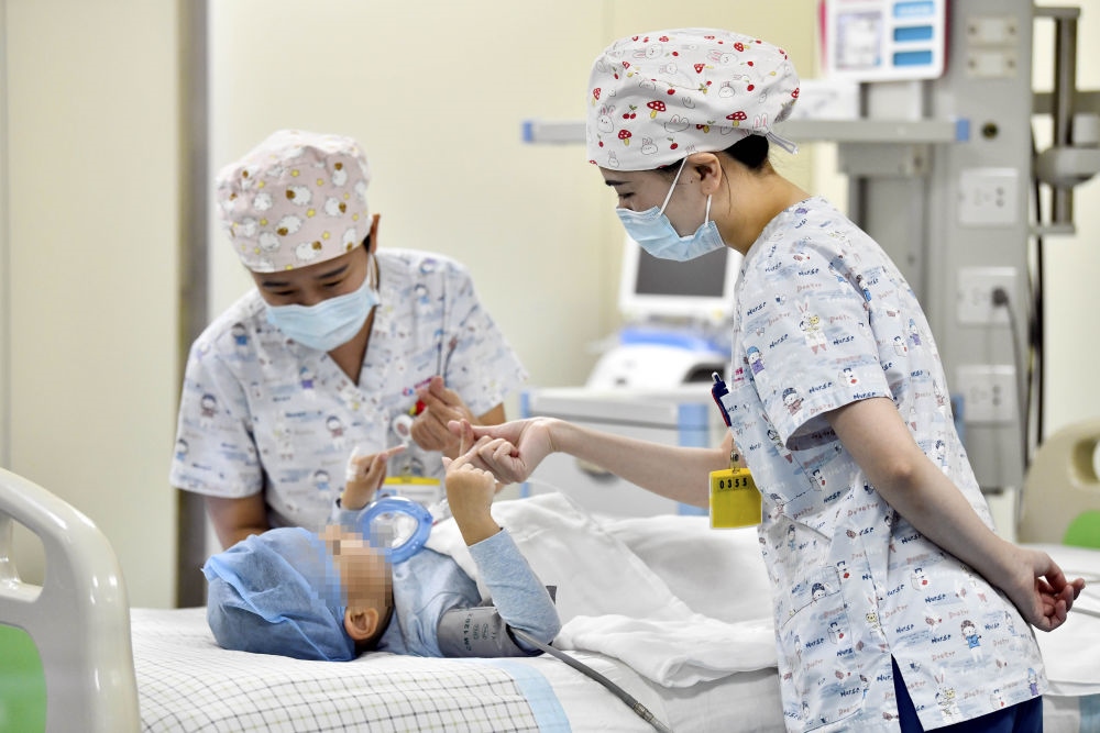 在山東省棗莊市婦幼保健院兒童ICU病房，醫(yī)護人員為完成靶向治療藥物諾西那生鈉的4歲脊髓性肌萎縮癥患兒加油鼓勁（2022年1月1日攝）。諾西那生鈉注射液是我國首個獲批治療脊髓性肌萎縮癥的進口藥物，2019年進入中國市場時，每針價格近70萬元。在2021年國家醫(yī)保目錄藥品談判中，以3.3萬元每針的價格進入新版醫(yī)保藥品目錄。新華社記者 郭緒雷 攝