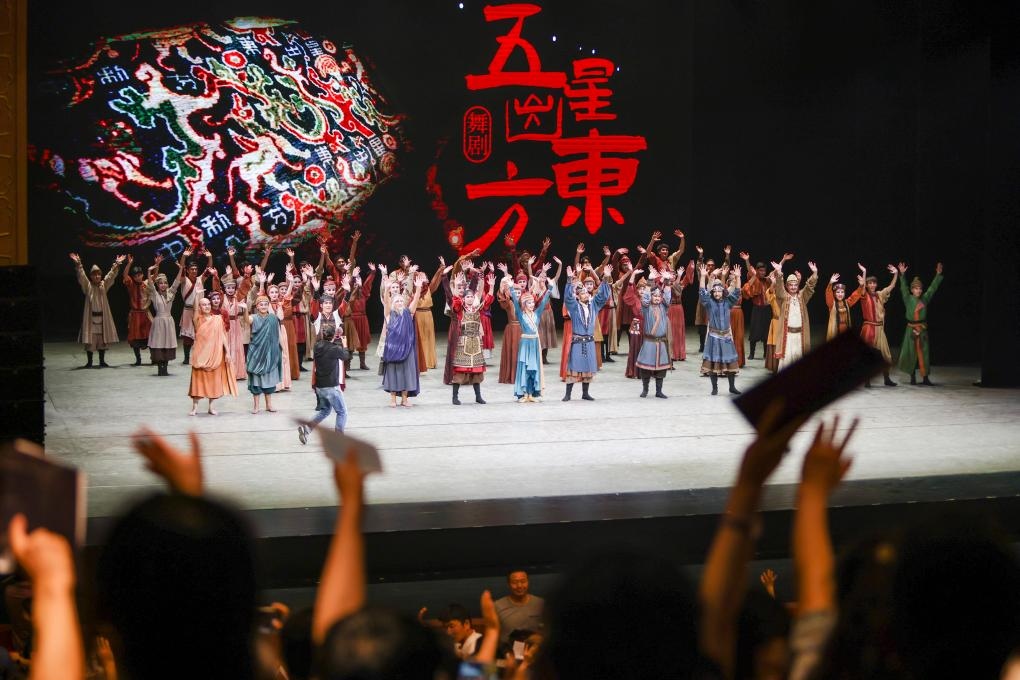 2023年7月31日，新疆和田地區(qū)新玉歌舞團(tuán)在烏魯木齊京劇院演出舞劇《五星出東方》后和觀(guān)眾互相揮手致意。這場(chǎng)演出是第六屆中國(guó)新疆國(guó)際民族舞蹈節(jié)的參演劇目之一，曾榮獲國(guó)家“文華獎(jiǎng)”等。新華社記者 郝昭 攝
