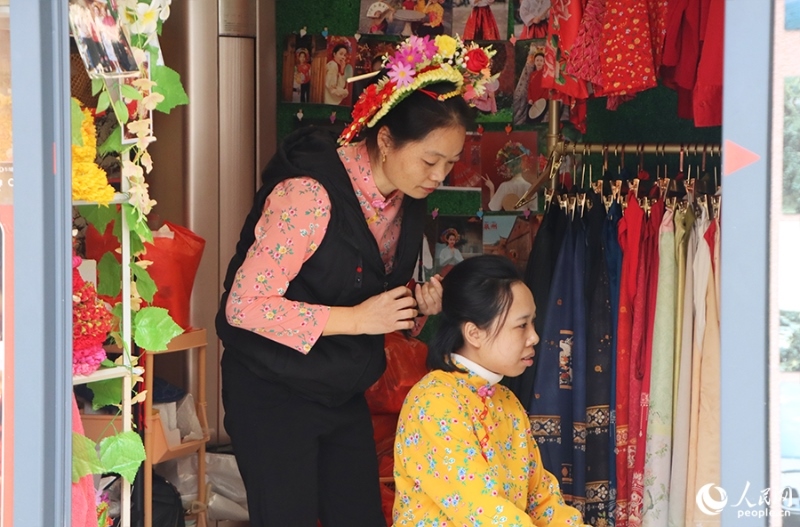 泉州府文廟附近，一名店主正為過(guò)路游客梳理頭發(fā)以佩戴“簪花圍”。人民網(wǎng) 黃東儀攝