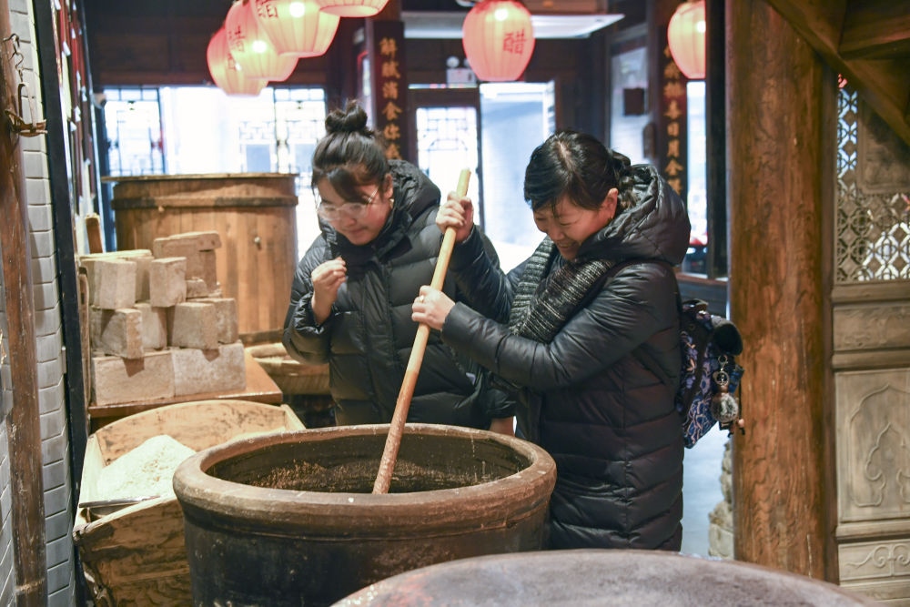 游客在平遙古城東湖老醋坊內(nèi)體驗陳醋發(fā)酵打耙（2022年1月28日攝）。新華社發(fā)（梁生仁攝）