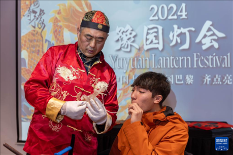 1月28日，在上海豫園舉行的民俗活動(dòng)上，美國(guó)馬斯卡廷中學(xué)學(xué)生在非遺傳承人的指導(dǎo)下吹糖偶。 新華社記者 王翔 攝