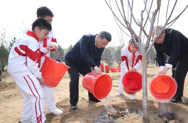 2024年4月3日，習(xí)近平總書記同少先隊(duì)員一起給剛栽下的樹苗澆水。