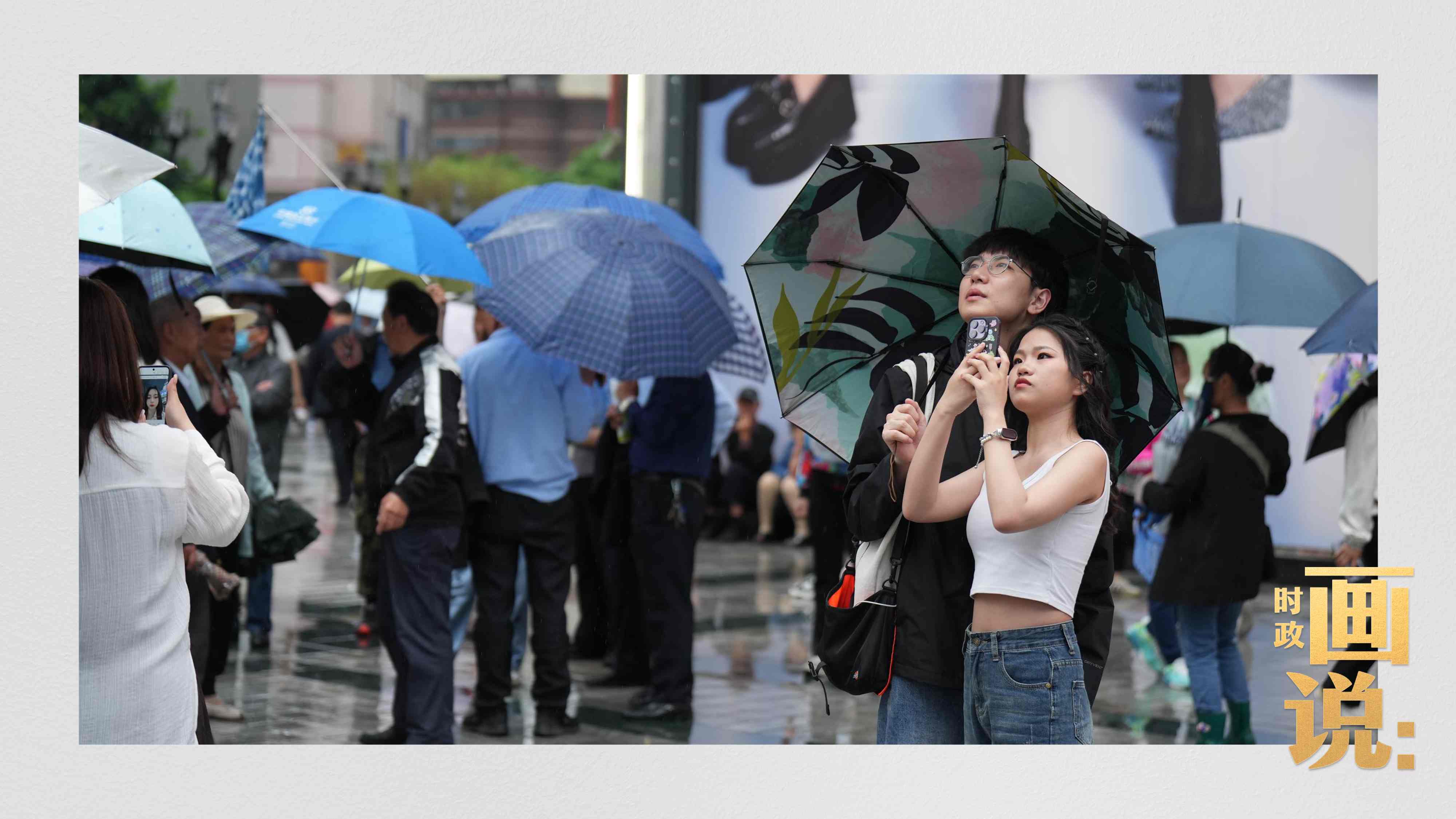 △細(xì)雨中的解放碑步行街，騎在父親肩膀的小女孩好奇張望。