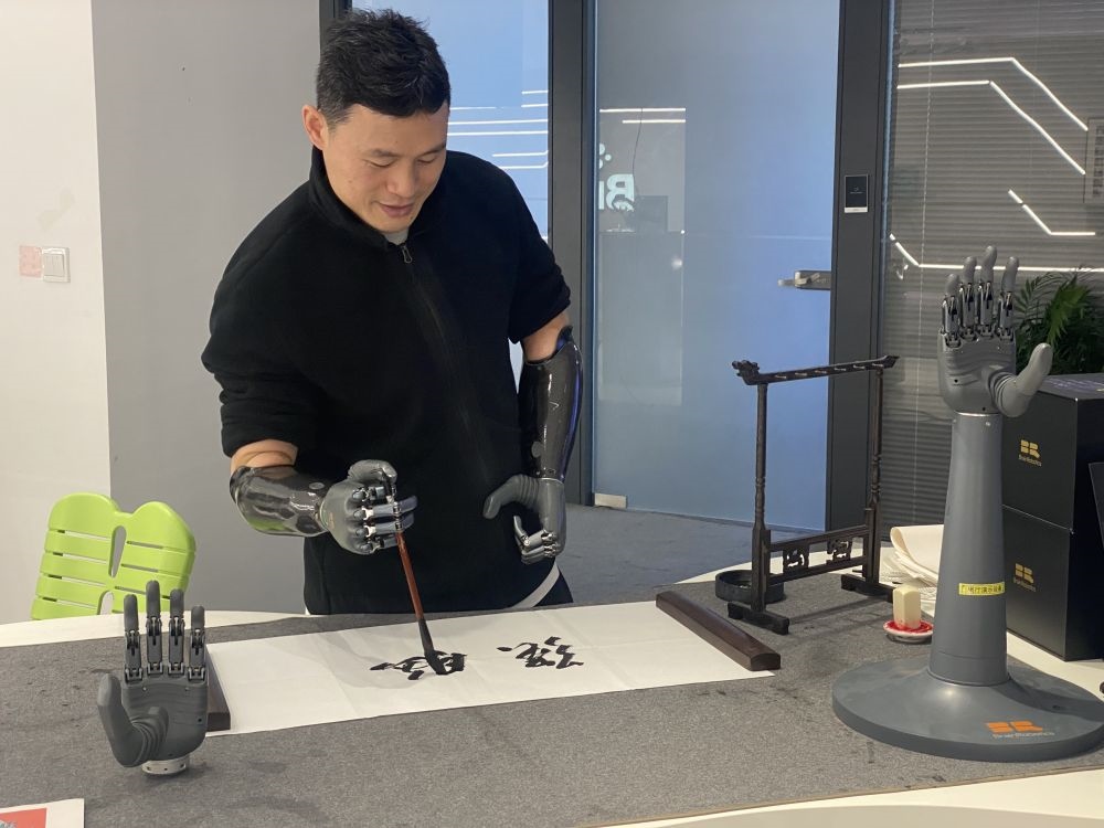 2024年3月29日，在浙江強腦科技有限公司展廳內(nèi)，失去雙手的產(chǎn)品體驗官倪敏成依靠智能仿生手寫毛筆字。新華社記者 魏一駿 攝