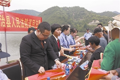 法院干警及相關(guān)部門工作人員對(duì)群眾進(jìn)行生態(tài)環(huán)境保護(hù)普法教育。