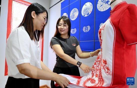 5月31日，在衡水市阜城縣一家剪紙工作室，游客在觀賞帶有剪紙元素的旗袍。