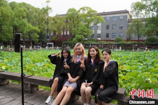 6月19日，時(shí)值一年畢業(yè)季，四川大學(xué)望江校區(qū)荷花池里的荷花盛開(kāi)，成為了畢業(yè)生們的打卡圣地，吸引了眾多畢業(yè)生拍照留念。圖為畢業(yè)生在荷花池邊拍照留念。中新社記者 安源 攝