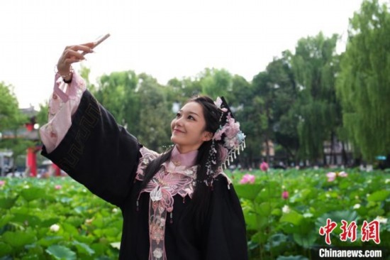 6月19日，時(shí)值一年畢業(yè)季，四川大學(xué)望江校區(qū)荷花池里的荷花盛開(kāi)，成為了畢業(yè)生們的打卡圣地，吸引了眾多畢業(yè)生拍照留念。圖為畢業(yè)生在荷花池邊拍照留念。中新社記者 安源 攝