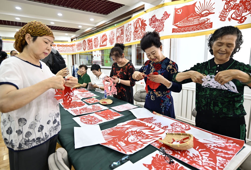 6月19日，長(zhǎng)城花園社區(qū)居民在社區(qū)“才藝堂”制作剪紙。