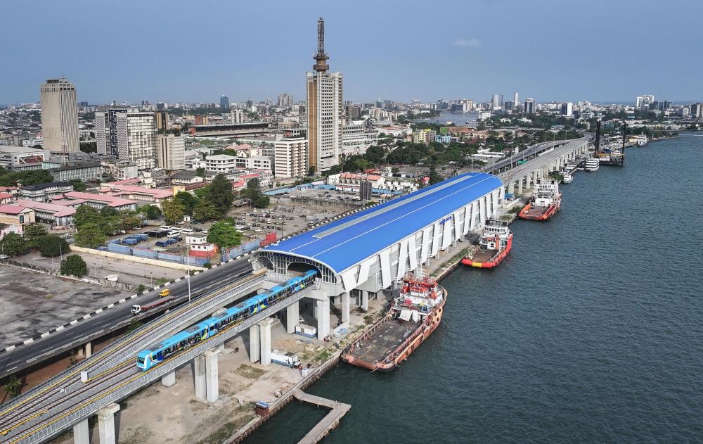 2024年3月2日，在尼日利亞拉各斯，一列輕軌藍線列車駛?cè)氪a頭站（無人機照片）。拉各斯輕軌藍線是西非地區(qū)首條由中國企業(yè)自主設(shè)計、建造、施工、運營的電氣化城市軌道交通項目。新華社記者 韓旭 攝