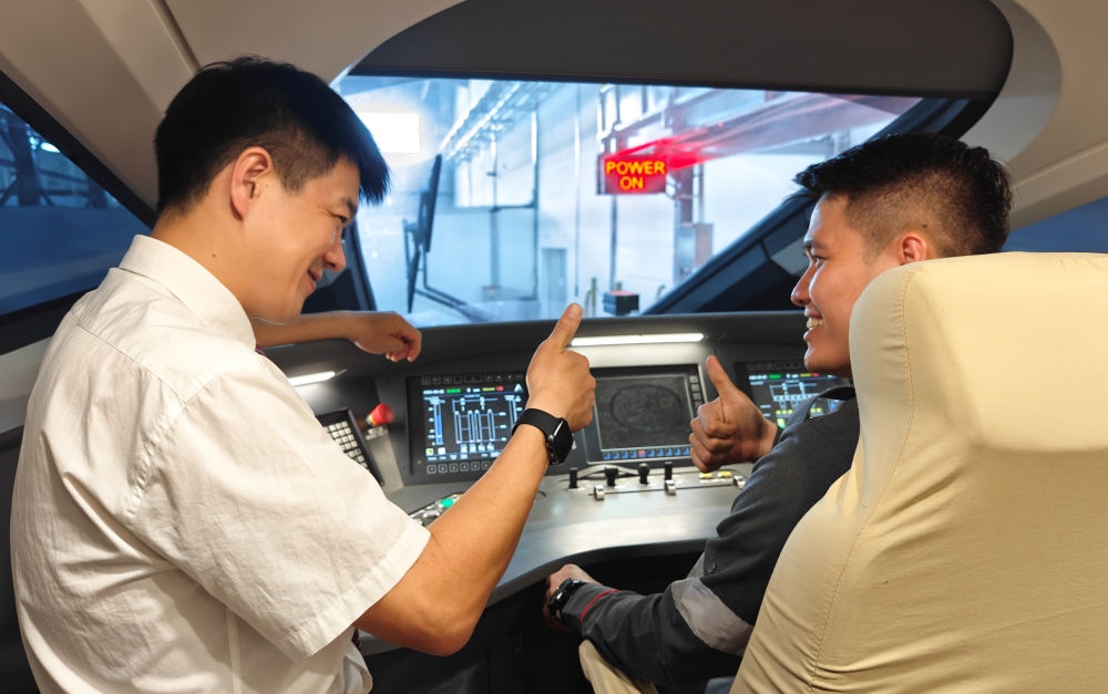 2023年8月25日，在印度尼西亞萬隆的雅萬高鐵德卡魯爾動車所內(nèi)，中國師傅穆振（左）向印尼火車司機塞蒂亞萬講解動車組出庫前的上電作業(yè)。新華社記者 徐欽 攝