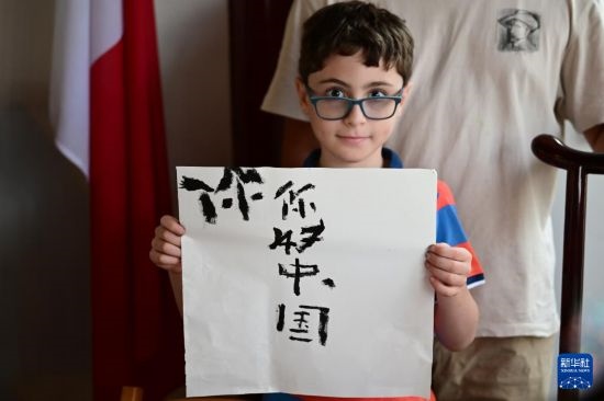 7月4日，在馬耳他桑塔露琪亞市的中國古典園林“靜園”，一名男孩展示他的書法作品。新華社發(fā)（喬納森·博格 攝）