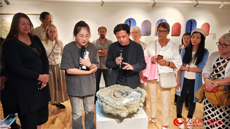 參展人、景德鎮(zhèn)陶瓷大學(xué)設(shè)計(jì)藝術(shù)學(xué)院副院長余劍峰（中）向來賓介紹參展作品。人民網(wǎng)記者 殷淼攝