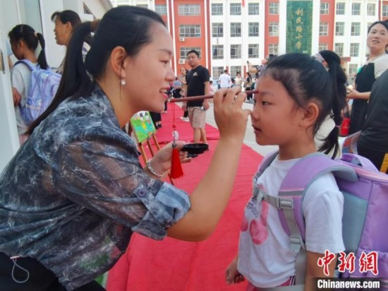 圖為衡水市利民路小學，老師為學生點朱砂痣，寓意開啟智慧。張松 攝