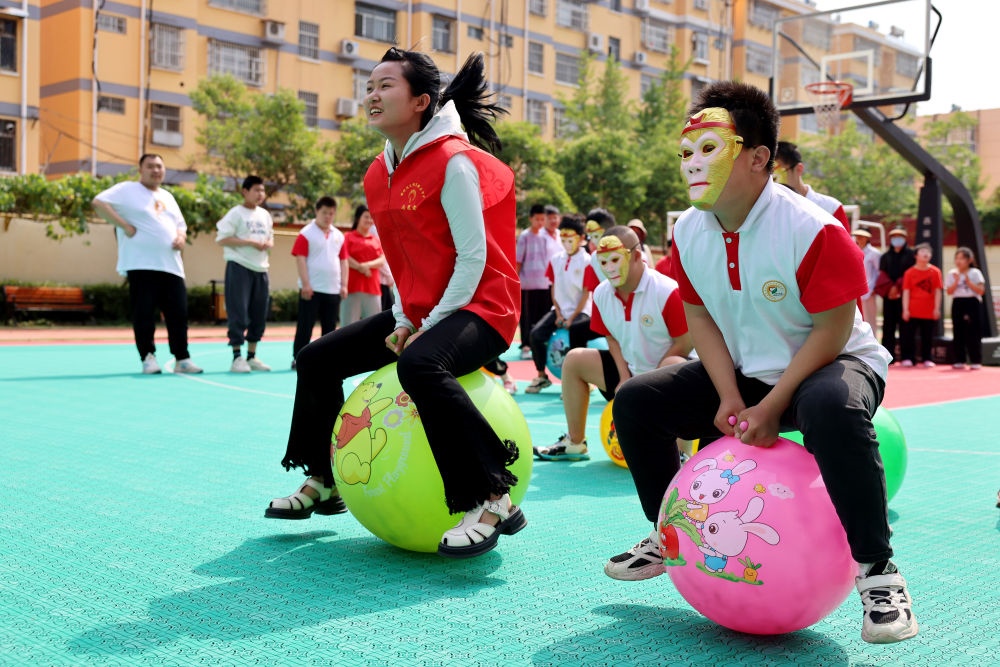 2024年5月17日，在山東省棗莊市市中區(qū)特殊教育中心，青年志愿者與智力障礙學生一起做游戲。新華社發(fā)（孫中喆攝）