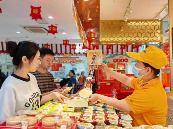 北京稻香村一家門店內(nèi)，售貨員向顧客展示新上市的月餅禮盒。（受訪者供圖）