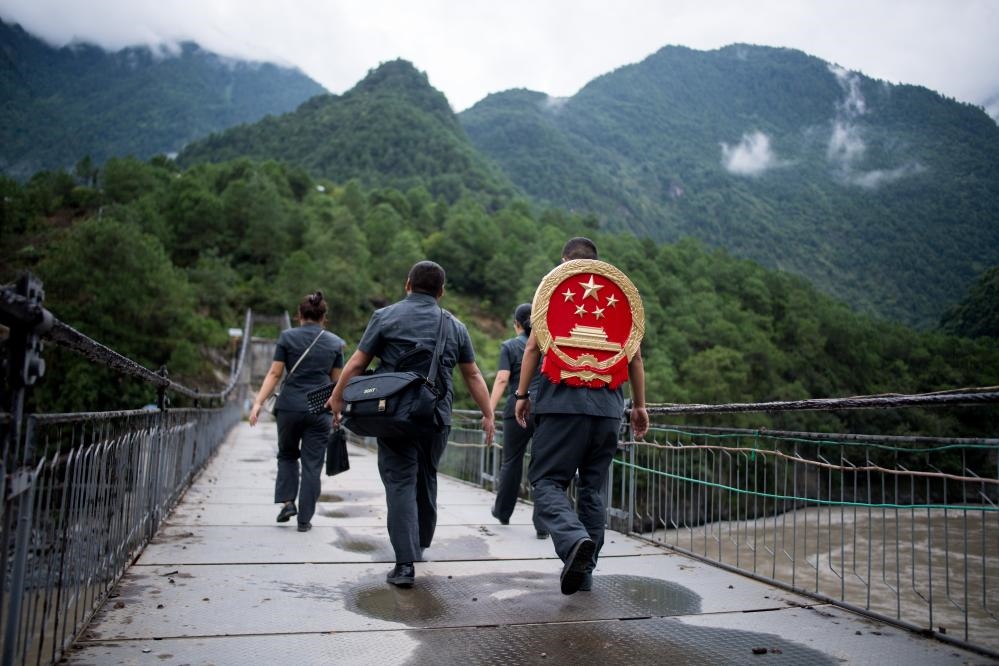 云南省怒江傈僳族自治州貢山縣人民法院法官鄧興背著國徽與同事們跨過怒江（2019年8月30日攝）。怒江高山峽谷眾多，交通不便，為方便群眾、更好地開展法律服務(wù)，背著國徽攀高山、過索橋、躲落石、鉆老林……成為鄧興法官的工作常態(tài)。新華社記者 江文耀 攝