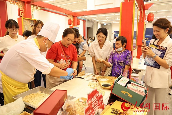 演出前，在天津桂發(fā)祥十八街麻花制作技藝非遺體驗(yàn)展臺(tái)前，泰國(guó)民眾體驗(yàn)天津麻花制作。人民網(wǎng)記者 楊一攝