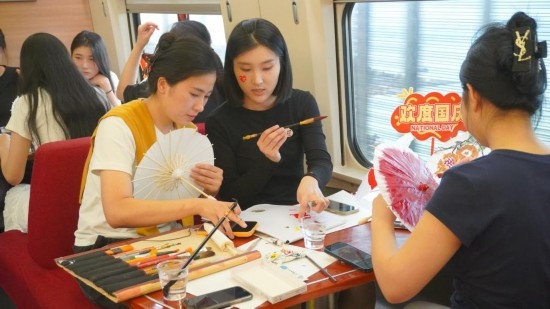 10月1日，旅客們?cè)贕1634次列車上給油紙傘作畫(huà)。新華社記者周義 攝