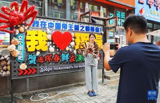 9月21日，游客在吉林省琿春市一處帝王蟹元素主題裝飾前拍照留念。新華社發(fā)