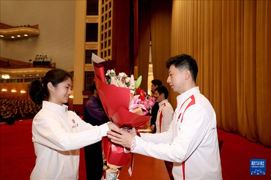 11月15日，一名學生代表在報告會上向乒乓球運動員馬龍（右）獻花。新華社記者 李明 攝
