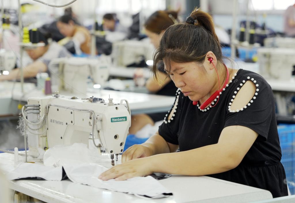 5月20日，村民在李寨村服裝加工廠內(nèi)忙碌。河南省周口市沈丘縣馮營(yíng)鎮(zhèn)李寨村地處豫東平原。近年來，乘著脫貧攻堅(jiān)與鄉(xiāng)村振興政策的東風(fēng)，李寨村積極探索產(chǎn)業(yè)發(fā)展模式，通過“龍頭企業(yè)+村集體經(jīng)濟(jì)+農(nóng)戶”的方式，逐漸發(fā)展形成肉牛養(yǎng)殖、設(shè)施農(nóng)業(yè)、服裝加工、康養(yǎng)民宿等產(chǎn)業(yè)，以產(chǎn)業(yè)振興助力鄉(xiāng)村振興。新華社記者 李嘉南 攝