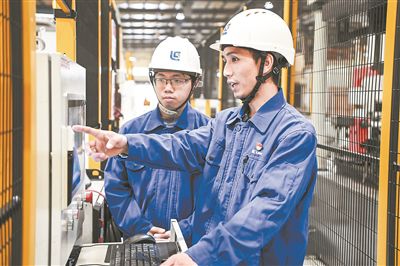 在廣西柳工機械股份有限公司生產車間內，一名高級技師（右）給徒弟講解數控設備操作細節(jié)。新華社記者 曹祎銘攝