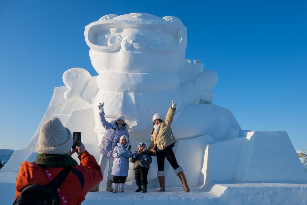 2025年1月3日，在黑龍江哈爾濱冰雪大世界園區(qū)，游客與亞冬會(huì)吉祥物雪雕“濱濱”合影