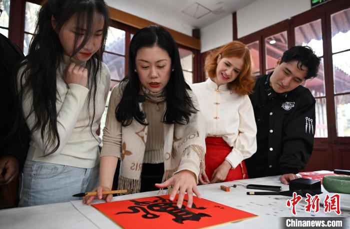 1月20日，西泠印社社員李硯（左二）為外籍留學(xué)生講述蛇年福字貼創(chuàng)作靈感。當(dāng)日，來自巴西、馬來西亞、加納、哈薩克斯坦的外籍留學(xué)生在浙江杭州西泠印社體驗(yàn)福貼、春聯(lián)和篆刻，感受古老的中國傳統(tǒng)文化。中新社記者 王剛 攝
