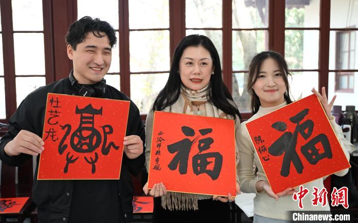 1月20日，外籍留學(xué)生和西泠印社社員李硯(中)展示各自創(chuàng)作的福貼。當(dāng)日，來自巴西、馬來西亞、加納、哈薩克斯坦的外籍留學(xué)生在浙江杭州西泠印社體驗(yàn)福貼、春聯(lián)和篆刻，感受古老的中國傳統(tǒng)文化。中新社記者 王剛 攝